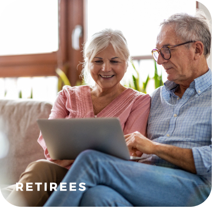Two retirees sitting on sofa looking at laptop