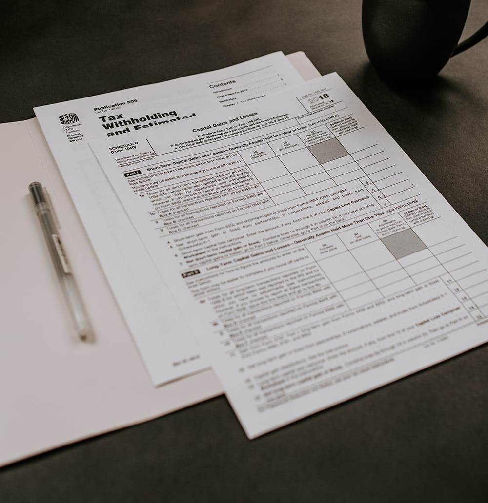 IRS capital-gains tax form on a desk with a pen and coffee mug.